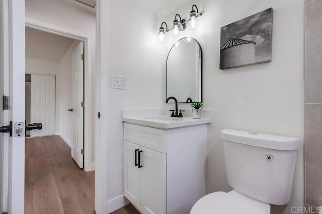 bathroom with hardwood / wood-style flooring, toilet, and vanity