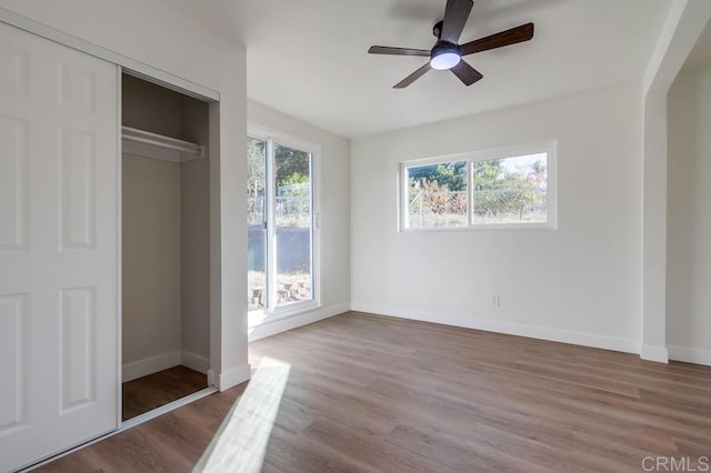 unfurnished bedroom featuring ceiling fan, wood-type flooring, and a closet