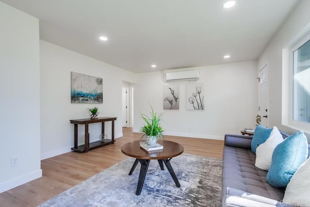 living room with a healthy amount of sunlight, light hardwood / wood-style floors, and a wall mounted air conditioner