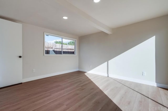 unfurnished room with beam ceiling and hardwood / wood-style floors