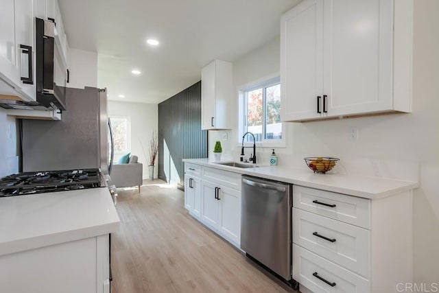 kitchen featuring white cabinets, sink, stainless steel appliances, and light hardwood / wood-style flooring