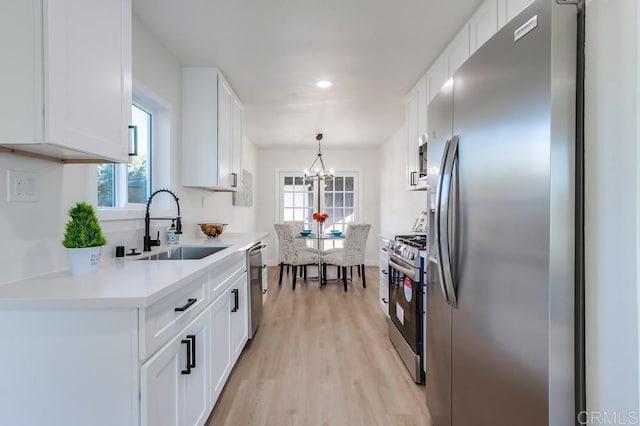 kitchen with a notable chandelier, appliances with stainless steel finishes, white cabinetry, and sink