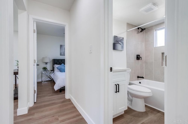 full bathroom with toilet, tiled shower / bath combo, hardwood / wood-style floors, and vanity