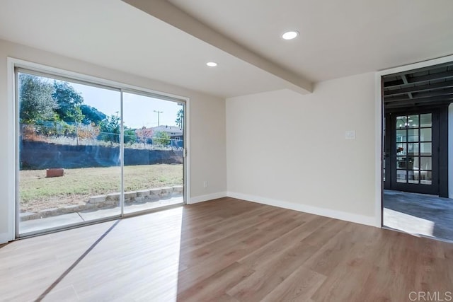 spare room featuring hardwood / wood-style flooring and beamed ceiling