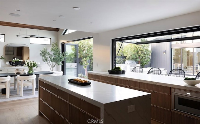 kitchen featuring oven, dark brown cabinets, light hardwood / wood-style floors, and a kitchen island