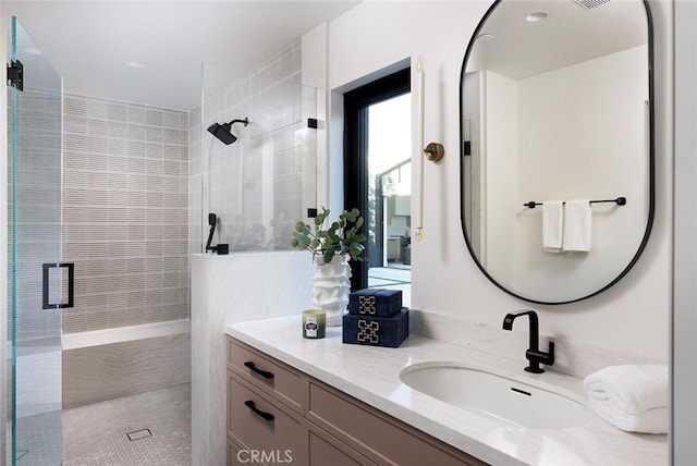 bathroom with a shower with shower door and vanity