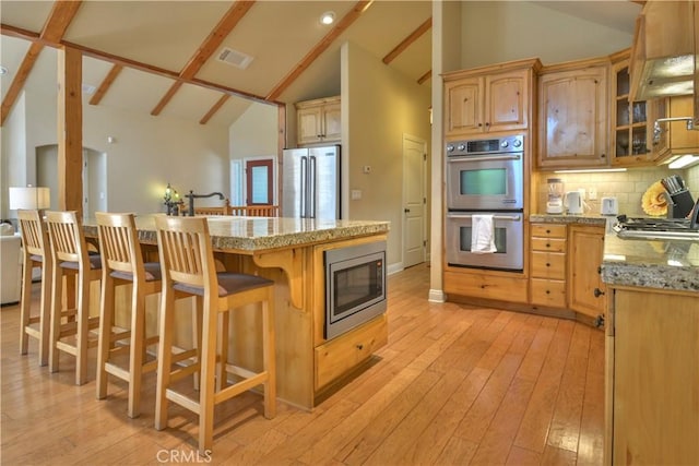 173 Grizzly Rd, Lake Arrowhead, CA 92352 - kitchen with stainless steel appliances, a breakfast bar area, backsplash, light wood-style flooring, and high vaulted ceiling