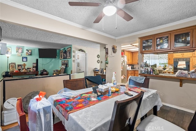 dining space with ceiling fan, wood-type flooring, crown molding, and a textured ceiling