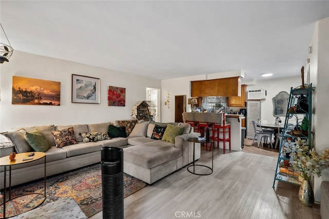 living room featuring an AC wall unit and light hardwood / wood-style floors