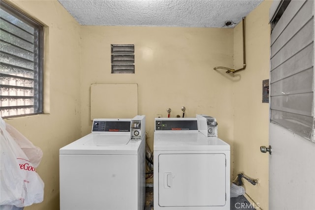 clothes washing area with separate washer and dryer and a textured ceiling