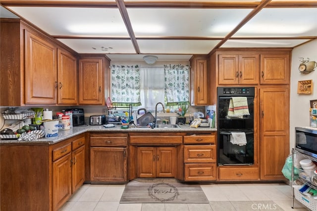 kitchen featuring light tile patterned floors, black double oven, and sink