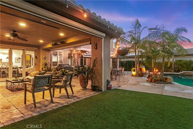 patio terrace at dusk featuring a yard and ceiling fan