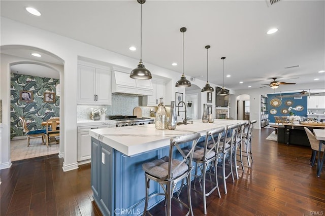 kitchen featuring hanging light fixtures, white cabinetry, custom range hood, and a spacious island