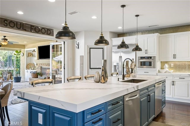 kitchen with sink, blue cabinetry, stainless steel oven, and white cabinets