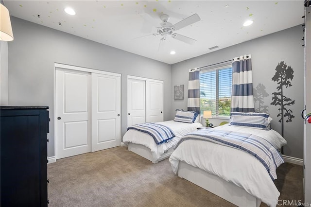 carpeted bedroom with two closets and ceiling fan