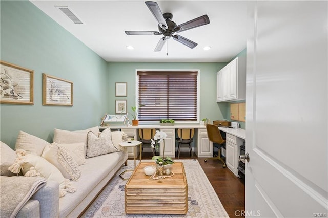 living room with built in desk, dark hardwood / wood-style floors, and ceiling fan