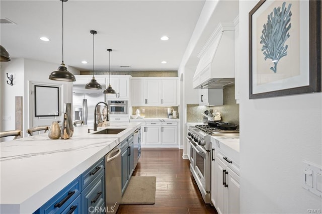 kitchen featuring blue cabinetry, sink, stainless steel appliances, a kitchen island with sink, and white cabinets