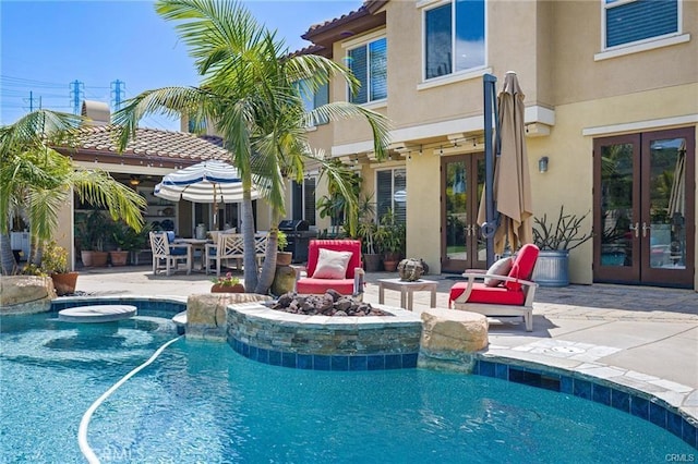 view of swimming pool featuring a patio, a fire pit, a grill, and french doors