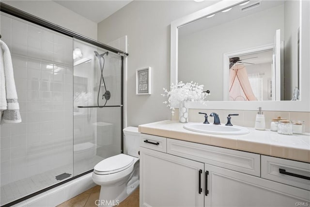 bathroom with vanity, a shower with shower door, tile patterned floors, and toilet