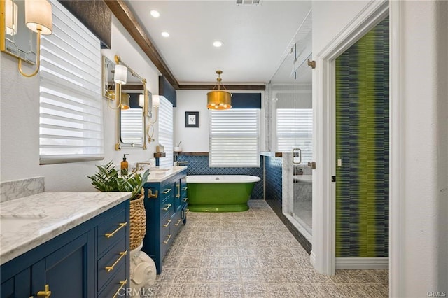 bathroom featuring independent shower and bath, vanity, ornamental molding, and tile walls