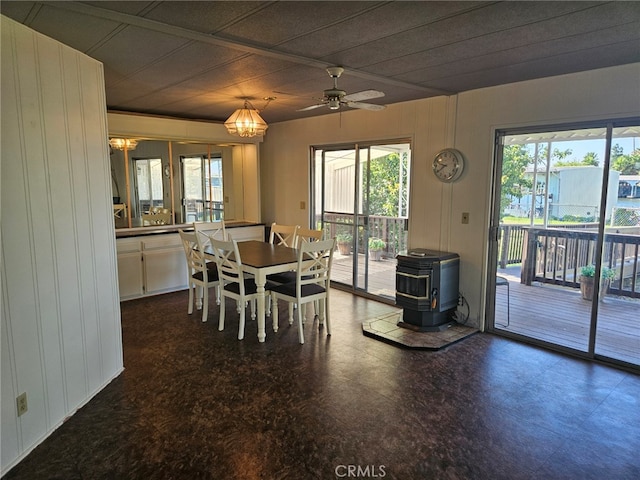 dining area featuring a wealth of natural light, ceiling fan with notable chandelier, and a wood stove