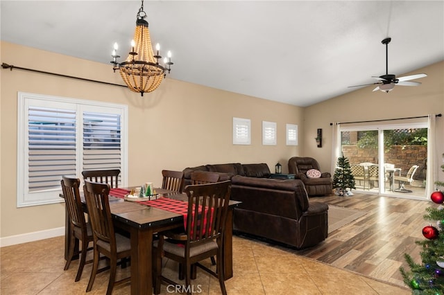 dining room with vaulted ceiling, light tile patterned floors, ceiling fan with notable chandelier, and baseboards