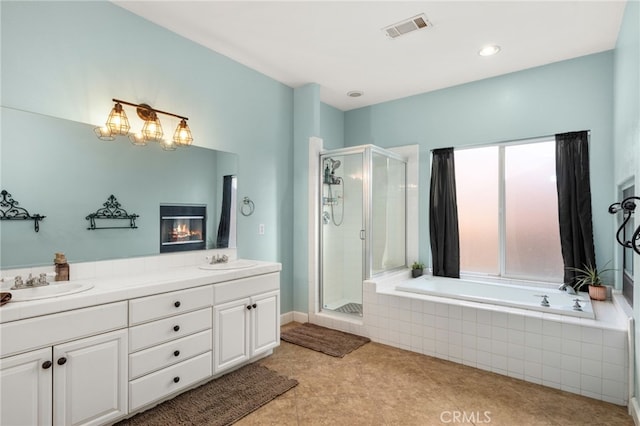 bathroom with a garden tub, a stall shower, a sink, and visible vents