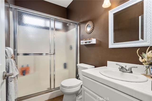 bathroom featuring a shower stall, toilet, and vanity