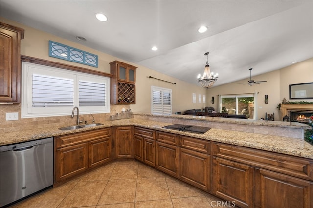 kitchen with light stone counters, a glass covered fireplace, a sink, dishwasher, and black electric cooktop