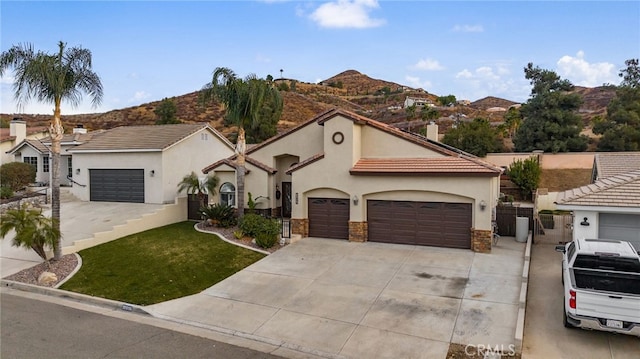 mediterranean / spanish-style home featuring stone siding, concrete driveway, a front lawn, and stucco siding