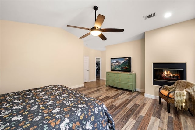 bedroom with lofted ceiling, visible vents, baseboards, and wood finished floors