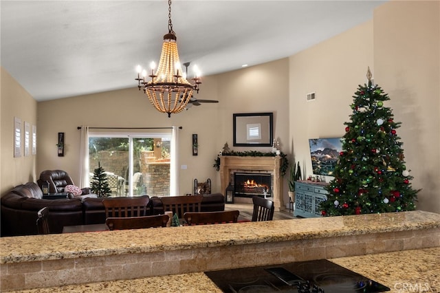 living room with lofted ceiling, a warm lit fireplace, visible vents, and an inviting chandelier