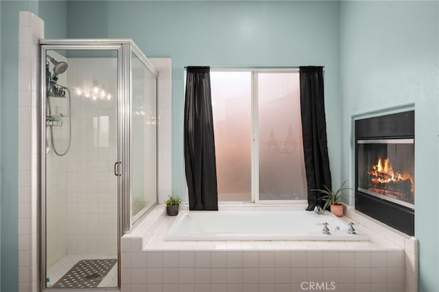 bathroom with a stall shower, a glass covered fireplace, and a bath