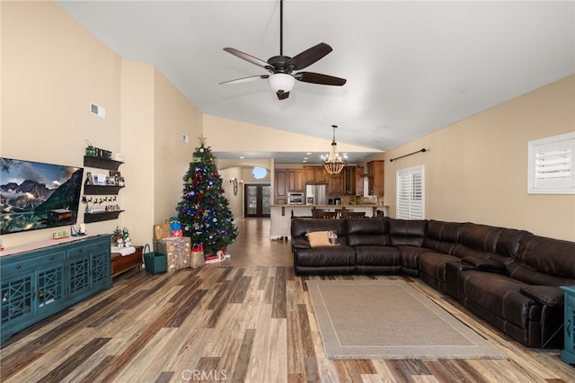 living area featuring ceiling fan with notable chandelier, lofted ceiling, visible vents, and wood finished floors