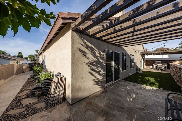 view of side of property with a patio area, fence, and stucco siding