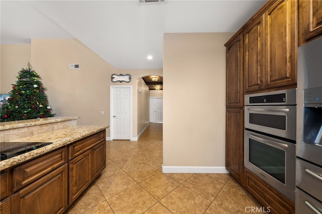 kitchen featuring light tile patterned floors, light stone counters, appliances with stainless steel finishes, and visible vents