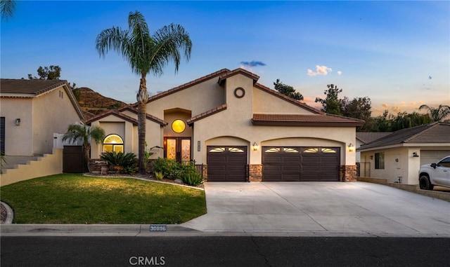 mediterranean / spanish-style house featuring a lawn and a garage