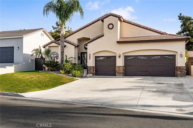 mediterranean / spanish-style home with driveway, stone siding, an attached garage, and stucco siding