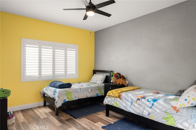 bedroom featuring a ceiling fan, baseboards, and wood finished floors