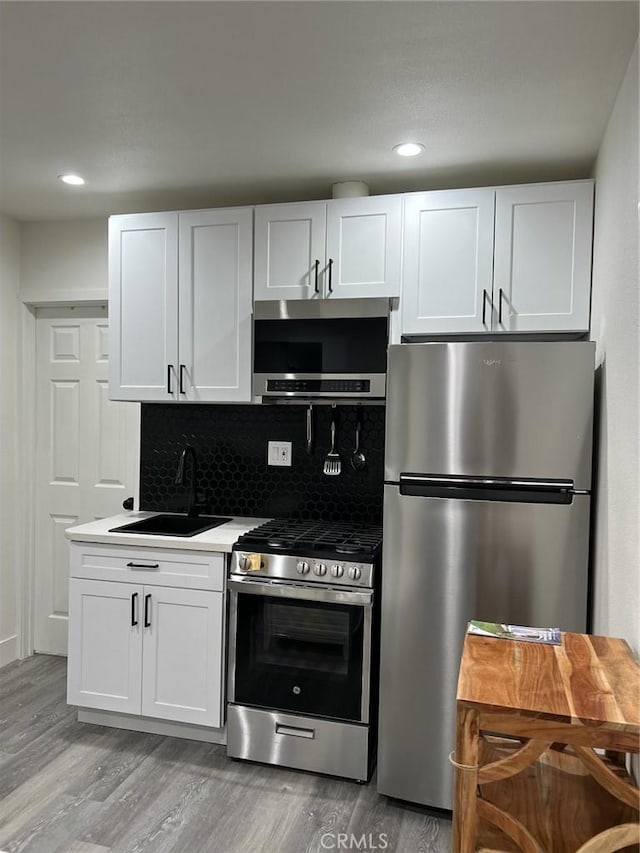 kitchen featuring backsplash, sink, white cabinetry, and appliances with stainless steel finishes