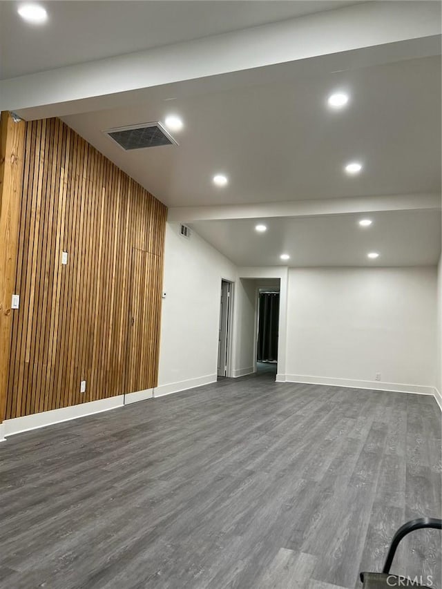 basement with dark hardwood / wood-style floors and wooden walls