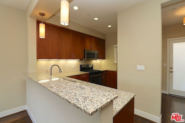 kitchen featuring decorative light fixtures, kitchen peninsula, appliances with stainless steel finishes, and sink