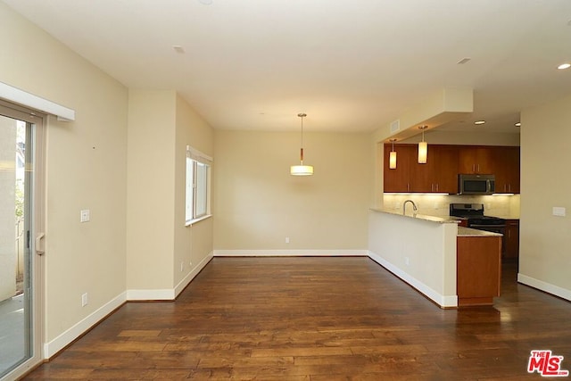 kitchen with pendant lighting, appliances with stainless steel finishes, sink, dark hardwood / wood-style floors, and kitchen peninsula