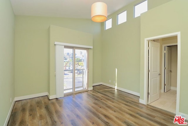 empty room with a towering ceiling and hardwood / wood-style flooring