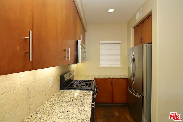 kitchen featuring decorative backsplash, light stone countertops, dark hardwood / wood-style floors, and stainless steel appliances