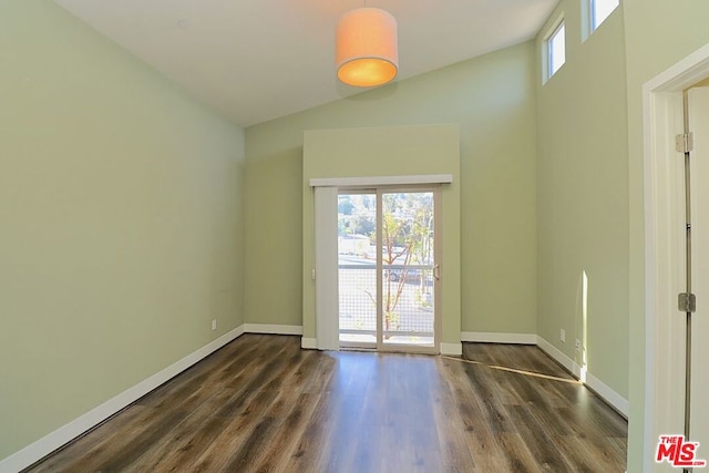 empty room with dark hardwood / wood-style flooring and lofted ceiling