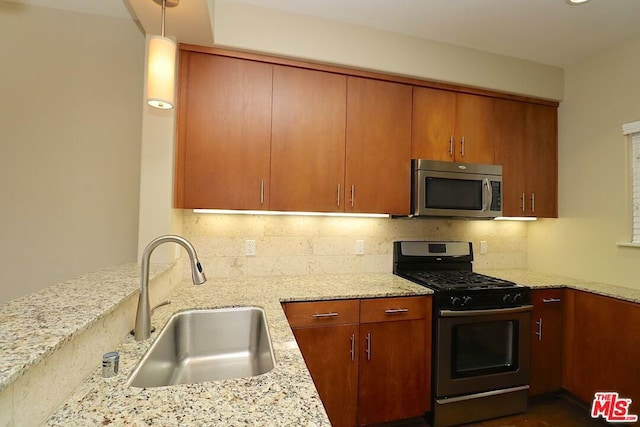 kitchen with light stone countertops, stainless steel appliances, tasteful backsplash, and sink