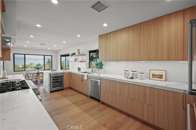 kitchen with appliances with stainless steel finishes, sink, wine cooler, and light stone counters