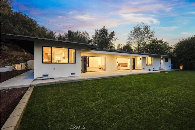 back house at dusk with a lawn