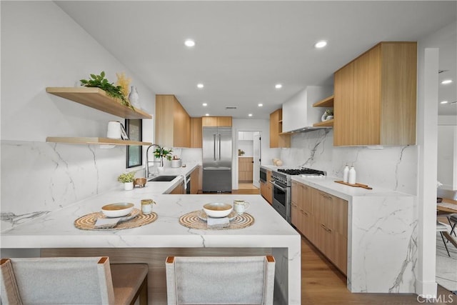 kitchen featuring sink, backsplash, a kitchen bar, high end appliances, and kitchen peninsula